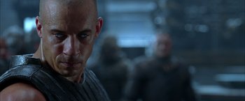 Movie still from “The Chronicles of Riddick” (2004), directed by David Twohy – A man with a bald head is looking at the camera; Close Up shot, Over the shoulder angle