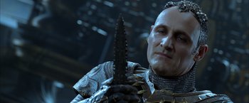 Movie still from “The Chronicles of Riddick” (2004), directed by David Twohy – A man in a suit of armor holding a sword; Close Up shot, Low angle