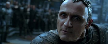 Movie still from “The Chronicles of Riddick” (2004), directed by David Twohy – A man's face with a bunch of people in the background; Close Up shot, Over the shoulder angle