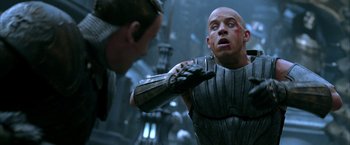 Movie still from “The Chronicles of Riddick” (2004), directed by David Twohy – A man in a black and silver outfit and a man in a white and black outfit; Close Up shot, Over the shoulder angle
