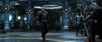 Movie still from “The Chronicles of Riddick” (2004), directed by David Twohy – A man in armor walks through a group of soldiers; Wide shot, Low angle