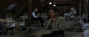 Movie still from “The Cider House Rules” (1999), directed by Lasse Hallström – A man sitting in front of another man in a room; Medium shot, High angle