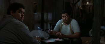 Movie still from “The Cider House Rules” (1999), directed by Lasse Hallström – A man sitting at a table with a cigarette in his mouth; Medium shot, Over the shoulder angle