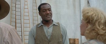 Movie still from “The Cider House Rules” (1999), directed by Lasse Hallström – A man standing in front of a white wall with a ladder; Medium shot, Low angle