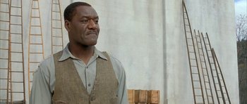 Movie still from “The Cider House Rules” (1999), directed by Lasse Hallström – A black man in a vest and a brown vest looking to his left; Close Up shot, Low angle