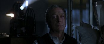 Movie still from “The Cider House Rules” (1999), directed by Lasse Hallström – An older man in a black vest looking at the camera; Close Up shot, Low angle