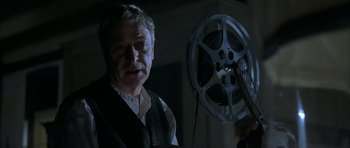 Movie still from “The Cider House Rules” (1999), directed by Lasse Hallström – An older man standing in front of a movie projector; Close Up shot, Low angle