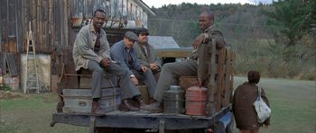 Movie still from “The Cider House Rules” (1999), directed by Lasse Hallström – A group of men sitting on top of a truck next to each other; Wide shot, Low angle