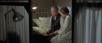 Movie still from “The Cider House Rules” (1999), directed by Lasse Hallström – An older man and woman sitting on a bed looking at a piece of paper; Medium shot, High angle