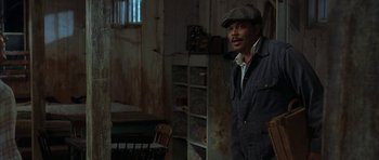 Movie still from “The Cider House Rules” (1999), directed by Lasse Hallström – A man standing in a room wearing a hat; Medium shot, High angle