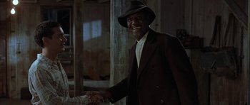 Movie still from “The Cider House Rules” (1999), directed by Lasse Hallström – A man in a hat shaking hands with another man in a suit; Medium shot, Low angle