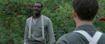 Movie still from “The Cider House Rules” (1999), directed by Lasse Hallström – A man standing in front of a tree with apples on it; Medium shot, Over the shoulder angle