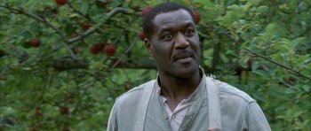 Movie still from “The Cider House Rules” (1999), directed by Lasse Hallström – A man standing in front of a tree with apples in the background; Close Up shot, Low angle