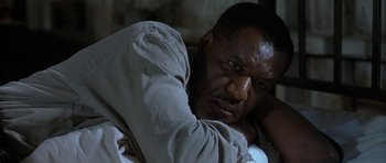 Movie still from “The Cider House Rules” (1999), directed by Lasse Hallström – A person sitting down with his arms crossed; Close Up shot, Low angle