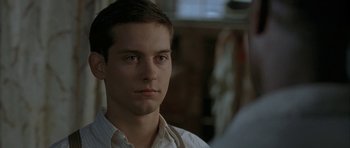 Movie still from “The Cider House Rules” (1999), directed by Lasse Hallström – A young man in a white shirt is looking at the camera; Close Up shot, Over the shoulder angle