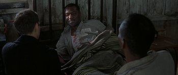 Movie still from “The Cider House Rules” (1999), directed by Lasse Hallström – An older man is laying in bed with a blanket over his body; Medium shot, Over the shoulder angle