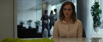 Movie still from “The Circle” (2017), directed by James Ponsoldt – A woman sitting at a table in front of a group of people; Close Up shot, Over the shoulder angle
