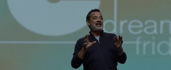 Movie still from “The Circle” (2017), directed by James Ponsoldt – A man standing in front of an audience with his hands in the air; Close Up shot, Over the shoulder angle