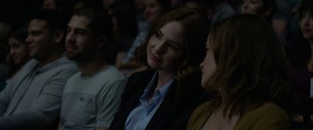 Movie still from “The Circle” (2017), directed by James Ponsoldt – A woman in a black suit and blue shirt is smiling at the camera; Close Up shot, Over the shoulder angle