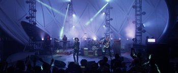 Movie still from “The Circle” (2017), directed by James Ponsoldt – A group of people on a stage with lights in the background; Wide shot, Low angle