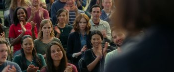 Movie still from “The Circle” (2017), directed by James Ponsoldt – A group of people sitting and standing in front of a crowd; Medium shot, Over the shoulder angle