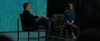 Movie still from “The Circle” (2017), directed by James Ponsoldt – A man and a woman sitting in chairs on a stage; Medium shot, Over the shoulder angle