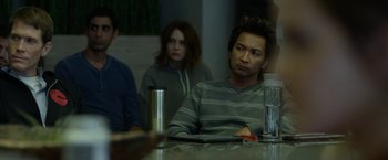 Movie still from “The Circle” (2017), directed by James Ponsoldt – A man sitting at a table in front of two other people; Medium shot, Over the shoulder angle