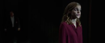 Movie still from “The Circle” (2017), directed by James Ponsoldt – A woman in a purple dress standing in front of a black background; Medium shot, Low angle
