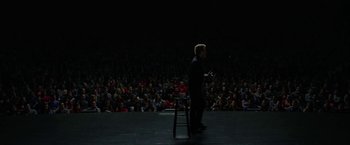 Movie still from “The Circle” (2017), directed by James Ponsoldt – A man standing in front of an audience on a stage; Wide shot, High angle