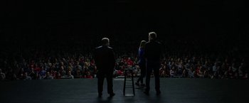 Movie still from “The Circle” (2017), directed by James Ponsoldt – A group of people standing on a stage in front of an audience; Wide shot, High angle
