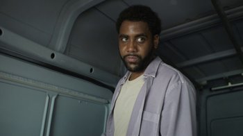 Movie still from “Full Circle” (2023), directed by Steven Soderbergh – A man in a white shirt and a gray jacket; Close Up shot, Low angle