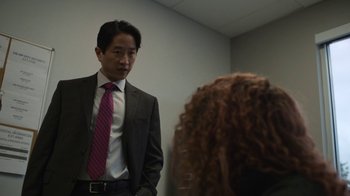 Movie still from “Full Circle” (2023), directed by Steven Soderbergh – A man wearing a suit and tie standing next to a woman; Medium shot, Over the shoulder angle