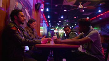 Movie still from “Full Circle” (2023), directed by Steven Soderbergh – A group of men sitting at a table playing cards; Wide shot, Low angle