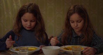 Movie still from “Petite Maman” (2021), directed by Céline Sciamma – Two young girls sitting at a dinner table; Medium shot, High angle