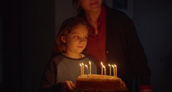 Movie still from “Petite Maman” (2021), directed by Céline Sciamma – A woman and a child holding a cake with lit candles; Close Up shot, High angle