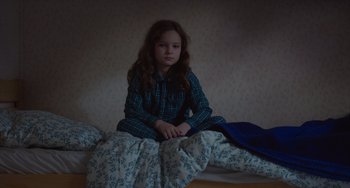 Movie still from “Petite Maman” (2021), directed by Céline Sciamma – A young girl sitting on a bed in a room; Medium shot, High angle