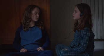 Movie still from “Petite Maman” (2021), directed by Céline Sciamma – Two young girls are sitting in a room; Medium shot, High angle
