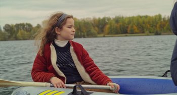 Movie still from “Petite Maman” (2021), directed by Céline Sciamma – A young girl sitting in a boat on the water; Medium shot, High angle