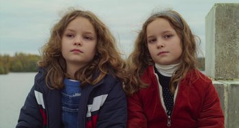Movie still from “Petite Maman” (2021), directed by Céline Sciamma – Two little girls sitting next to each other; Close Up shot, High angle