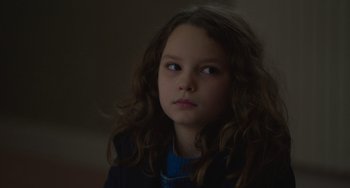 Movie still from “Petite Maman” (2021), directed by Céline Sciamma – A young girl with long curly brown hair looking to her left; Close Up shot, Over the shoulder angle