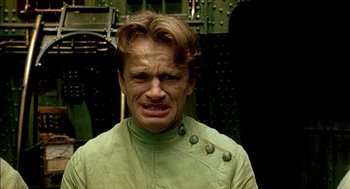 Movie still from “The City of Lost Children” (1995), directed by Jean-Pierre Jeunet – A man in a green shirt with buttons on his chest; Close Up shot, Low angle