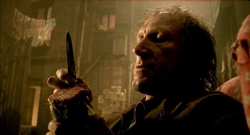 Movie still from “The City of Lost Children” (1995), directed by Jean-Pierre Jeunet – A man holding a knife in his hand; Close Up shot, High angle
