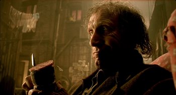 Movie still from “The City of Lost Children” (1995), directed by Jean-Pierre Jeunet – An old man holding a piece of food in his hand; Close Up shot, Low angle