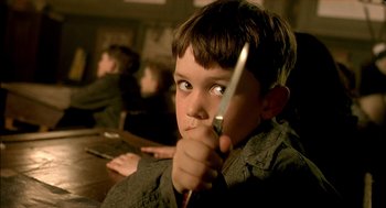 Movie still from “The City of Lost Children” (1995), directed by Jean-Pierre Jeunet – A young boy holding a knife in his hand; Close Up shot, High angle