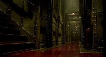Movie still from “The City of Lost Children” (1995), directed by Jean-Pierre Jeunet – A dark hallway with a red floor and a metal door; Extreme Wide shot, High angle