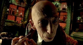 Movie still from “The City of Lost Children” (1995), directed by Jean-Pierre Jeunet – An old man with a bald head is holding a brush; Close Up shot, Low angle