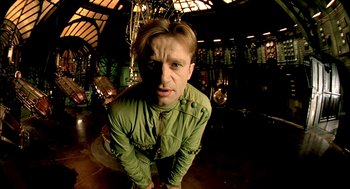 Movie still from “The City of Lost Children” (1995), directed by Jean-Pierre Jeunet – A man in a green jacket crouching in a room; Close Up shot, Low angle
