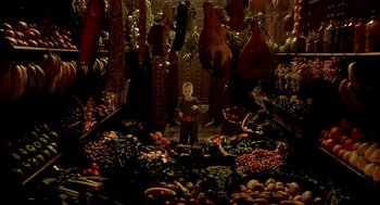 Movie still from “The City of Lost Children” (1995), directed by Jean-Pierre Jeunet – A child standing in front of an abundance of fruits and vegetables; Wide shot, Overhead angle