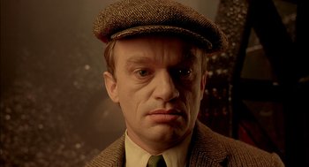 Movie still from “The City of Lost Children” (1995), directed by Jean-Pierre Jeunet – A person wearing a hat and a suit; Close Up shot, High angle