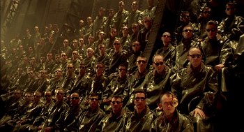 Movie still from “The City of Lost Children” (1995), directed by Jean-Pierre Jeunet – A group of men wearing sunglasses sitting in a row; Extreme Wide shot, High angle